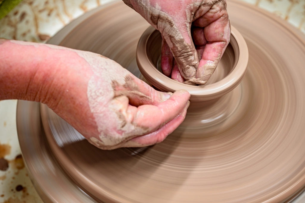 Hands shaping clay on a potter's wheel
